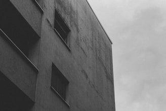 A black and white photograph capturing an empty urban corner with subtle shadows and textures.