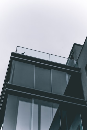 A modern architectural structure with glass panels and a minimalist design, showcasing clean lines and a geometric pattern.