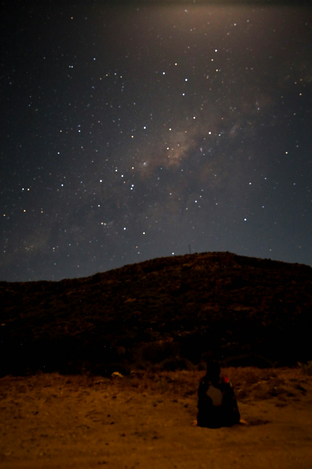 person sitting under starry sky at night