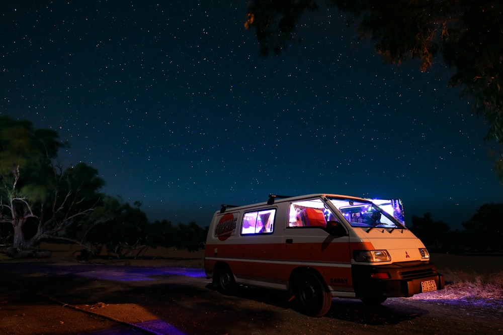 white Mitsubishi L300 parked near tree under starry sky