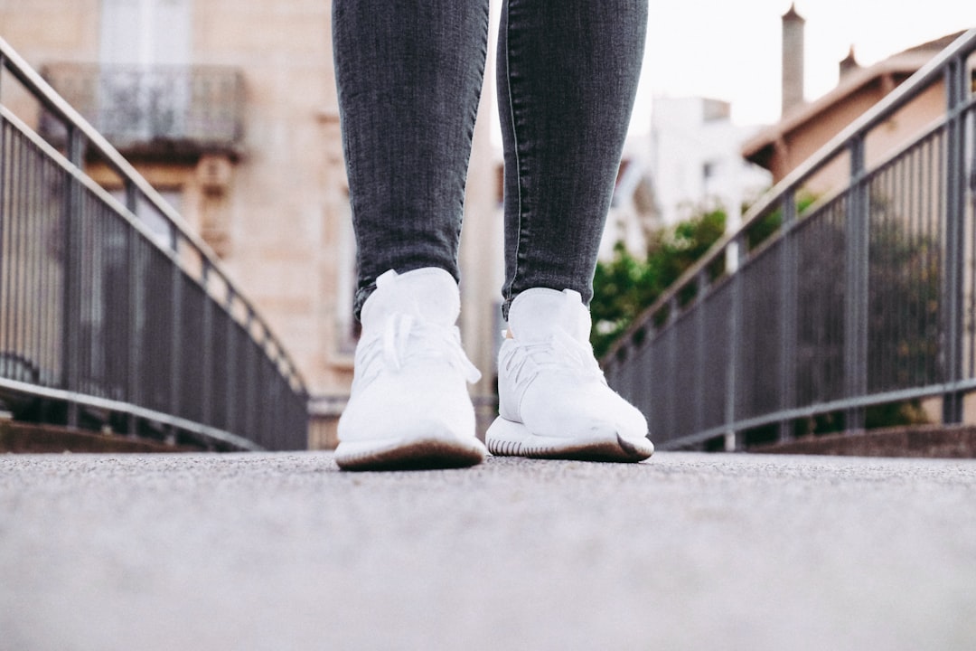 person walking on pavement wearing white shoes