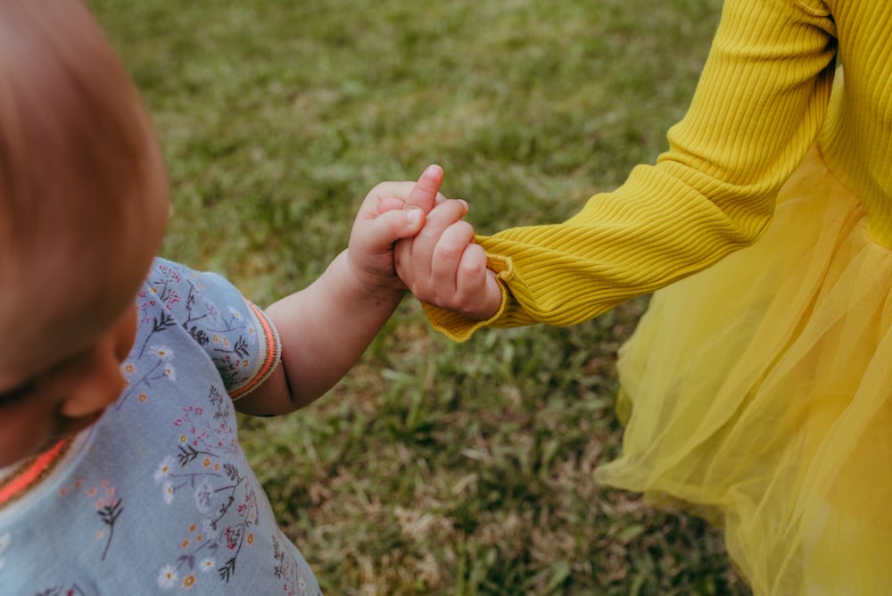 two toddler's holding hands during daytime