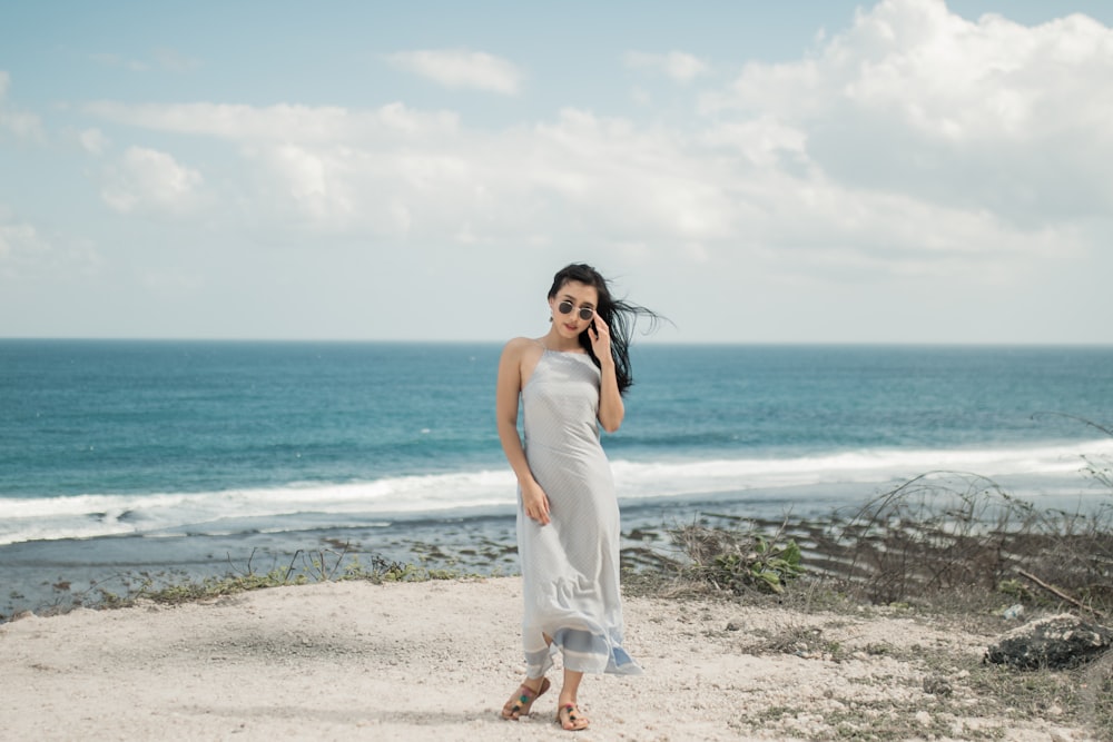 woman in white dress standing on seashore