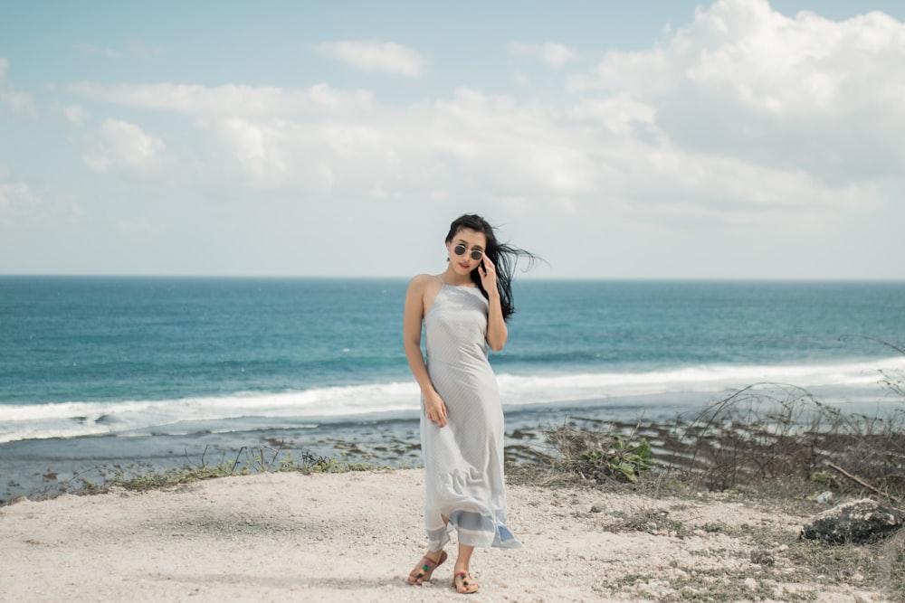 donna in vestito bianco in piedi in riva al mare