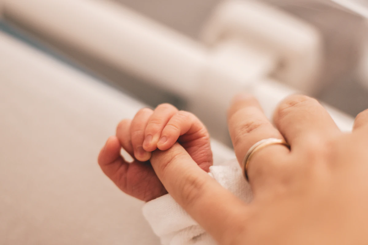 Mão de bebê segurando o dedo da mãe — uropediatria