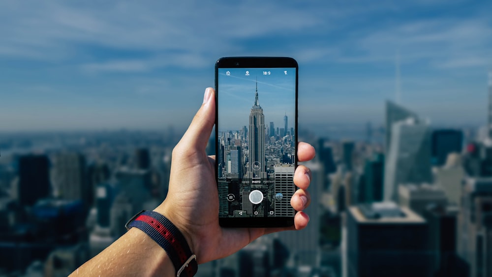 person taking photo of gray tower