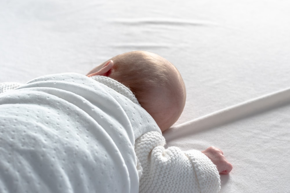 baby lying on white surface