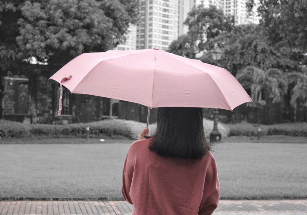 foto de foco raso da pessoa segurando o guarda-chuva rosa