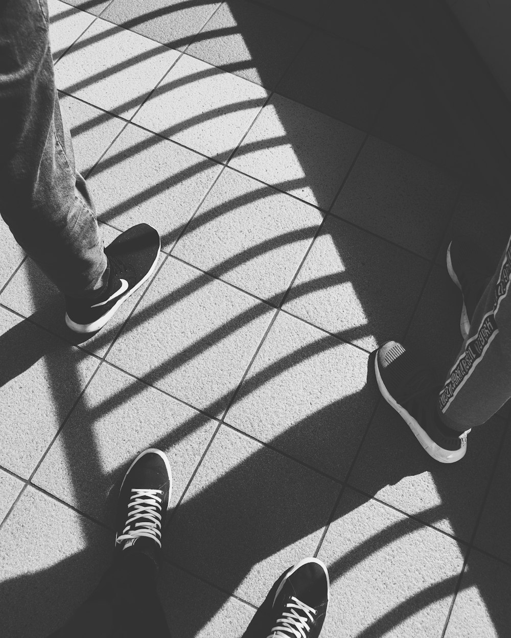 grayscale photography of three person in black sneakers