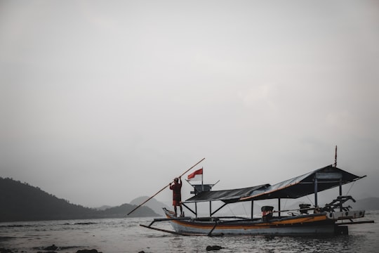 man standing on boat during foggy day in Lampung Indonesia