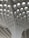 A modern architectural ceiling design featuring a series of geometric patterns and recessed lighting. The structure is composed of a grid-like pattern with curved, intersecting lines leading upwards.