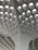 A modern architectural ceiling design featuring a series of geometric patterns and recessed lighting. The structure is composed of a grid-like pattern with curved, intersecting lines leading upwards.