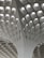 A modern architectural ceiling design featuring a series of geometric patterns and recessed lighting. The structure is composed of a grid-like pattern with curved, intersecting lines leading upwards.