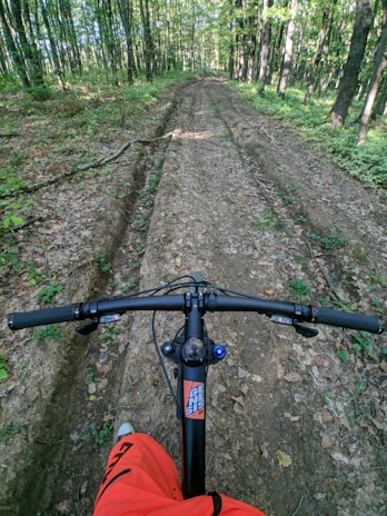 A sleek bioalien sports camera mounted on a mountain bike handlebar, capturing a rider speeding down a forest trail.