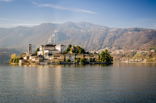 concrete buildings surrounded by body of water during daytime in San Giulio Island Italy