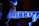 A close-up view of an electric guitar being played, with a focus on the fretboard and fingers. The image is illuminated with a blue and purple light, creating a luminous, almost ethereal effect on the guitar and the player's hands.