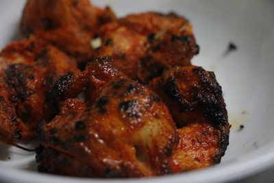 A close-up of juicy grilled chicken glazed with a rich flavvafull marinade under warm lighting.