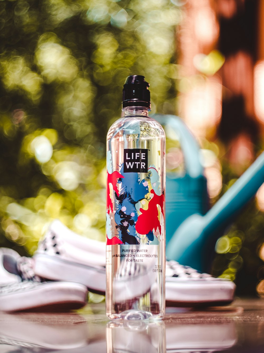 LIFE WTR bottle near black-and-white slip-on shoes