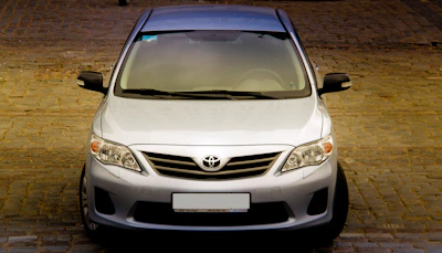 Front view of a sleek, silver second-hand sedan parked on a sunny street.