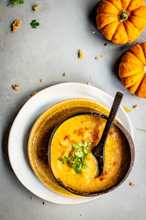 A steaming bowl of creamy pumpkin soup garnished with toasted seeds and a swirl of cream