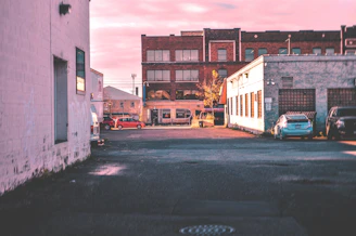 A quiet city alley at dawn, empty except for soft light casting long shadows, rendered in rich black and white.