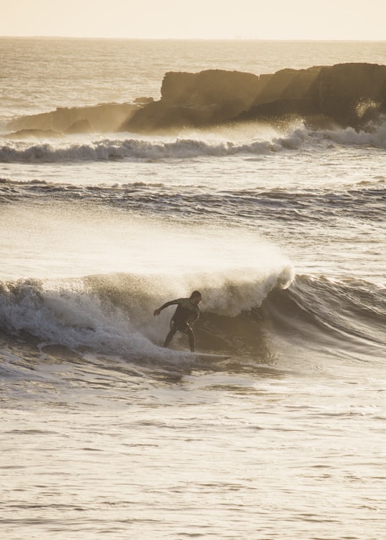 man surfing on waves in Estoril Portugal