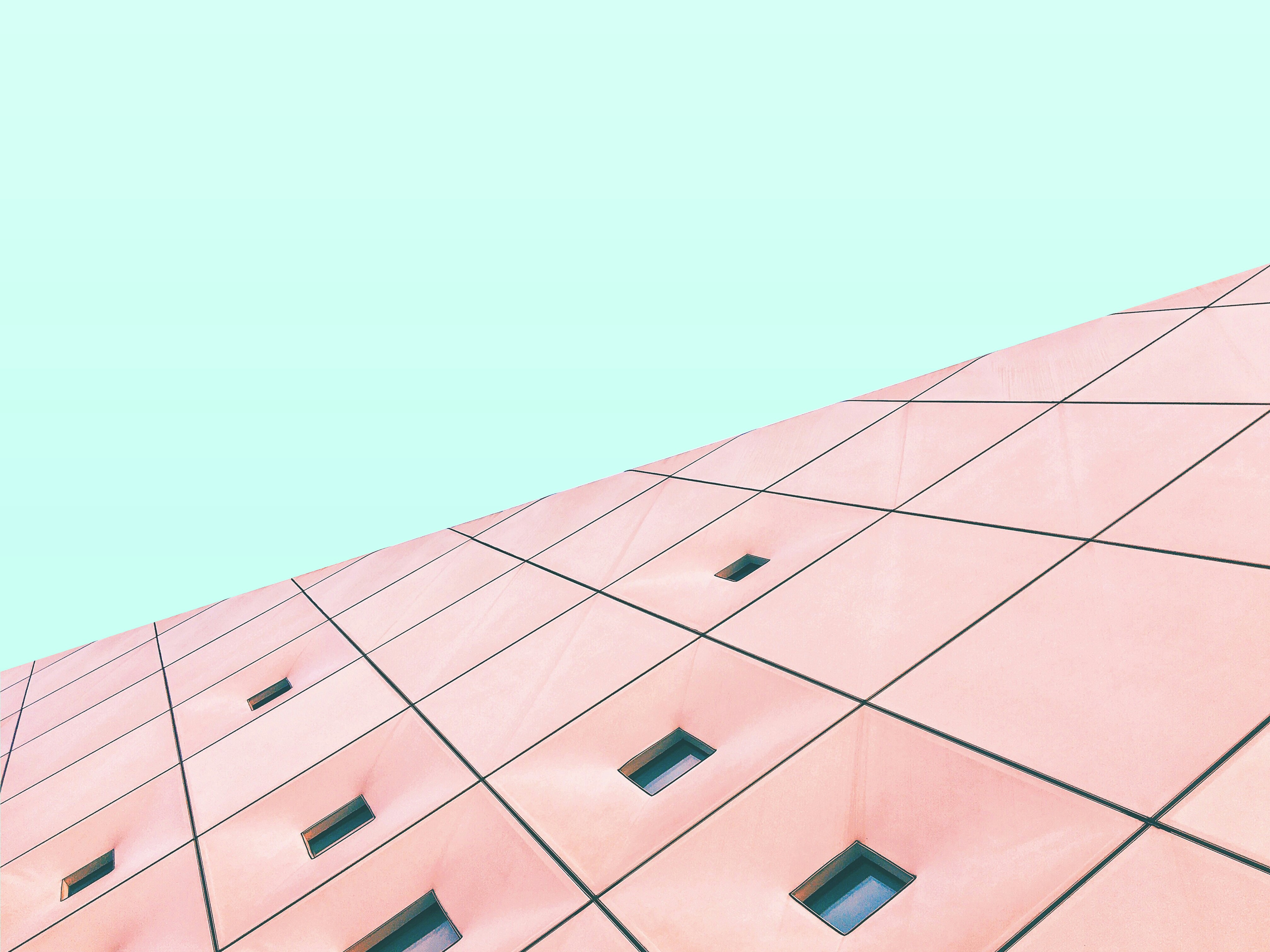 a pink building with several windows and a sky background