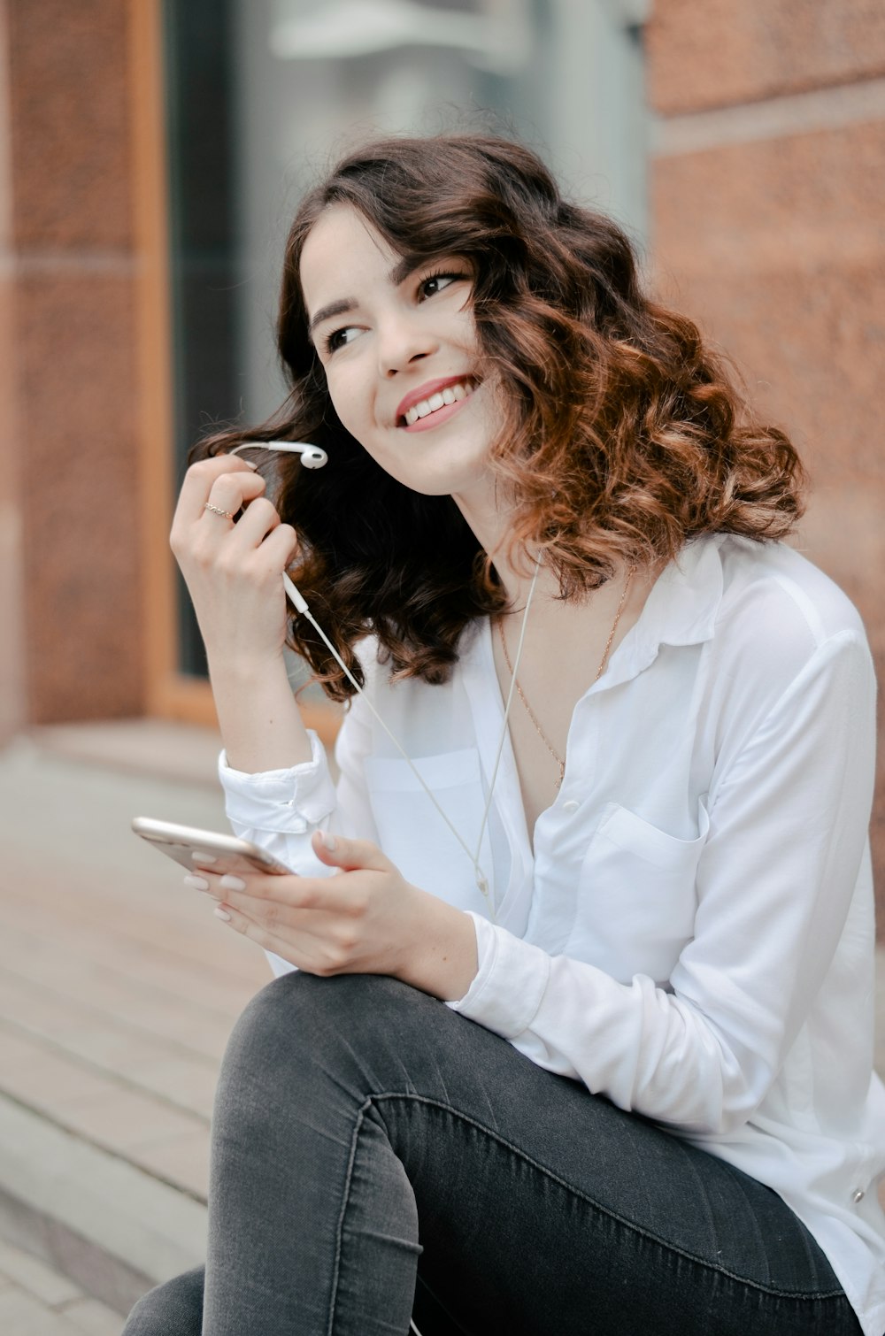 woman in white dress shirt holding smartphone