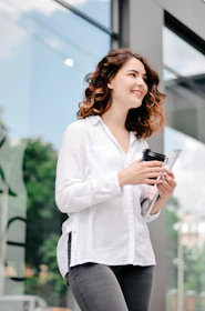 A woman reviewing her budget and smiling with a cup of coffee nearby.