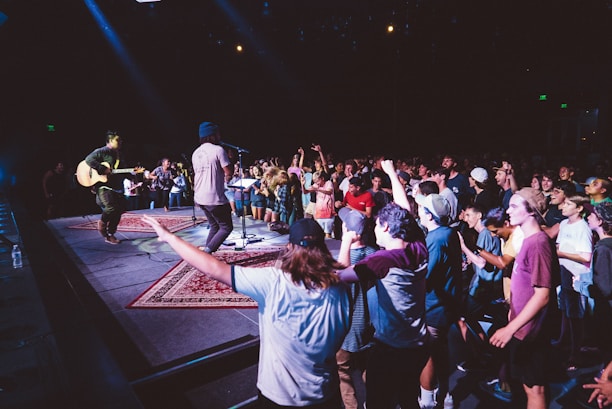 A musician performing on stage with an audience enjoying the music.