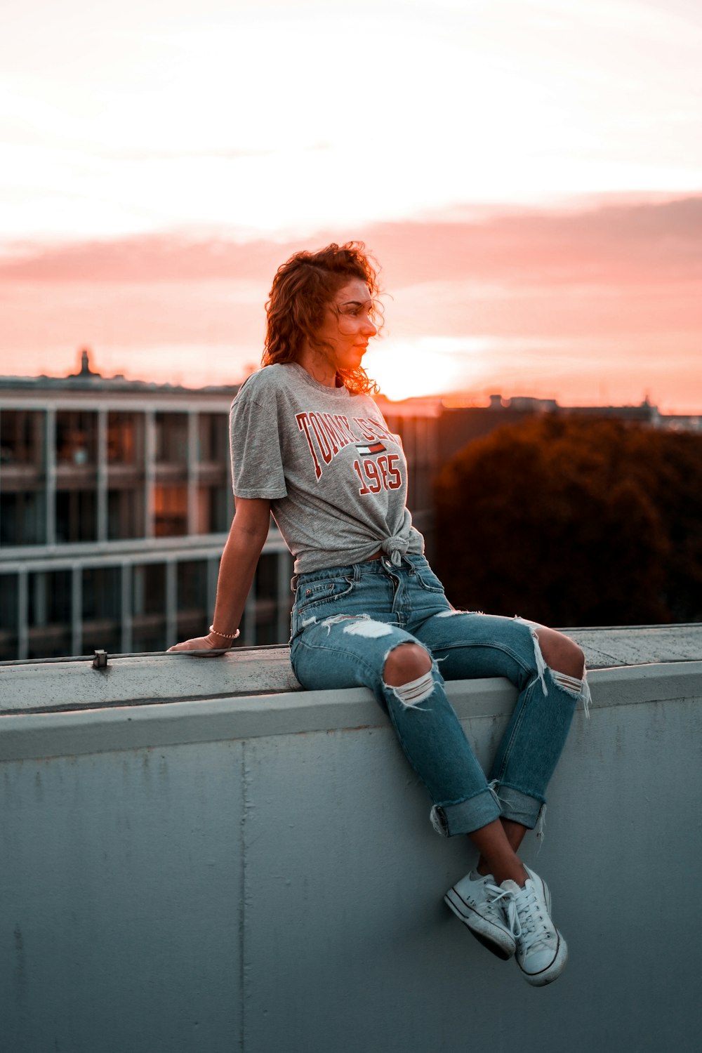 woman sitting on gray concrete wall