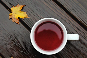 Close-up of a coffee mug featuring the 'rewired stories' logo, surrounded by autumn leaves.