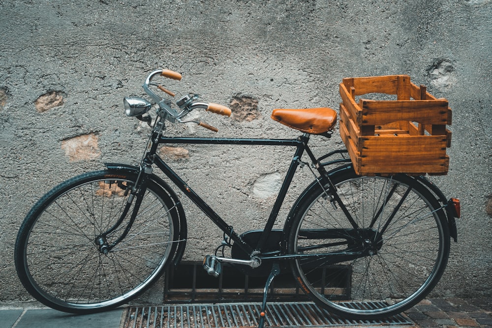 black commuter bike parked beside gray wall