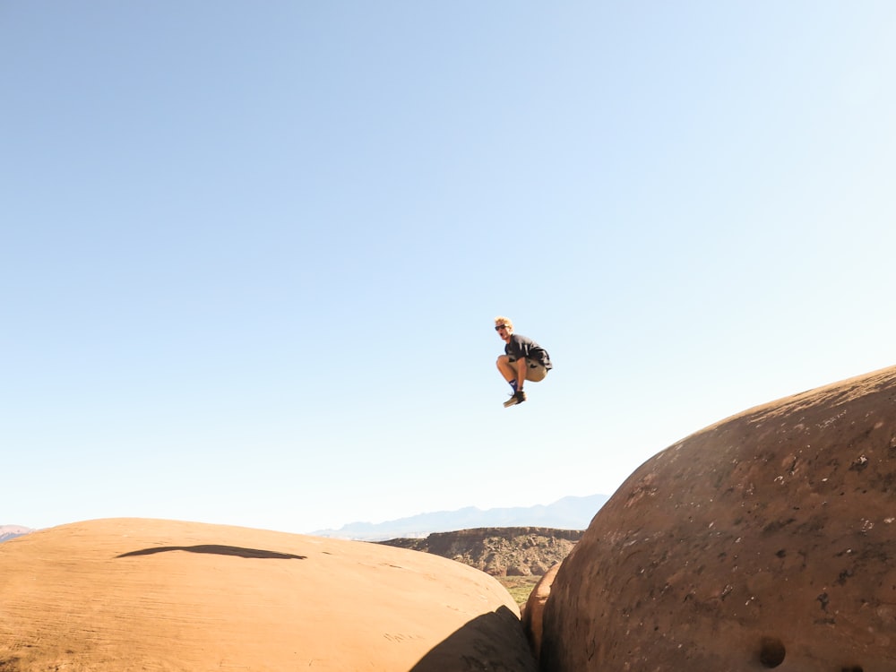 man jumping on rock formation at daytime