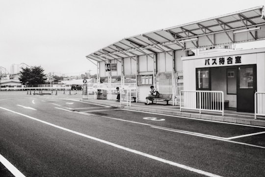 grayscale photo of two person sitting on bench near building in Fujiyoshida Japan