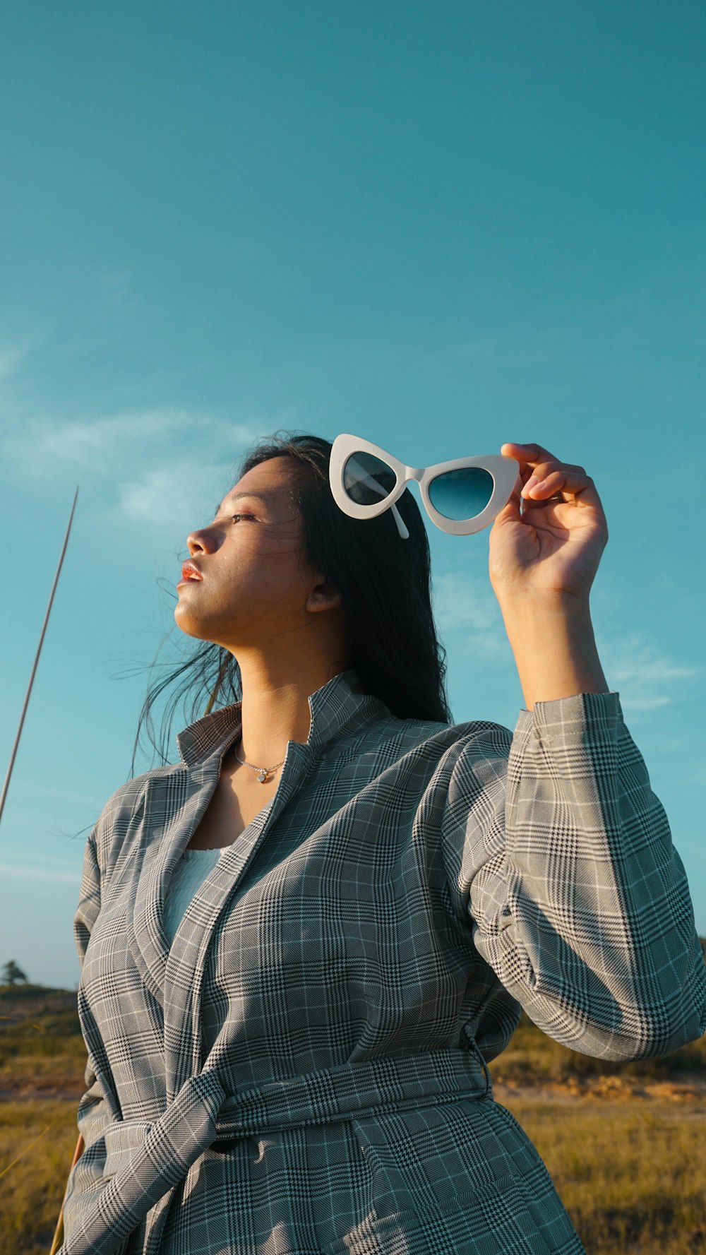 woman wearing grey coat holding sunglasses