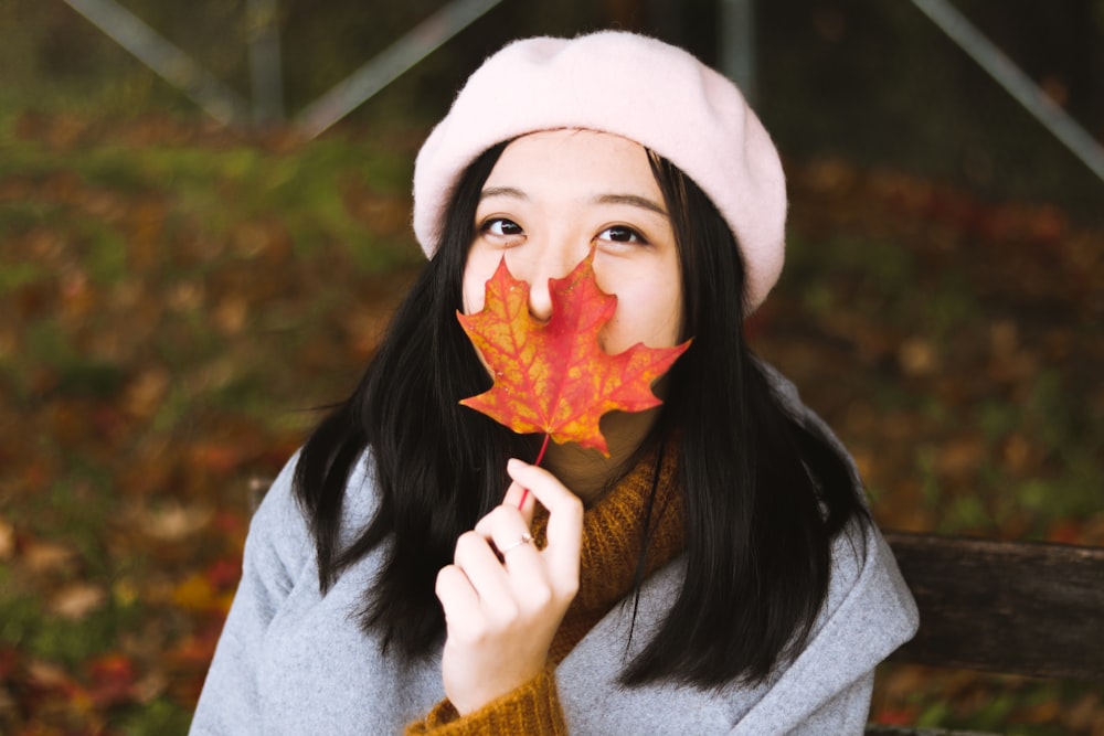 woman holding maple leaf and wearing pink hat