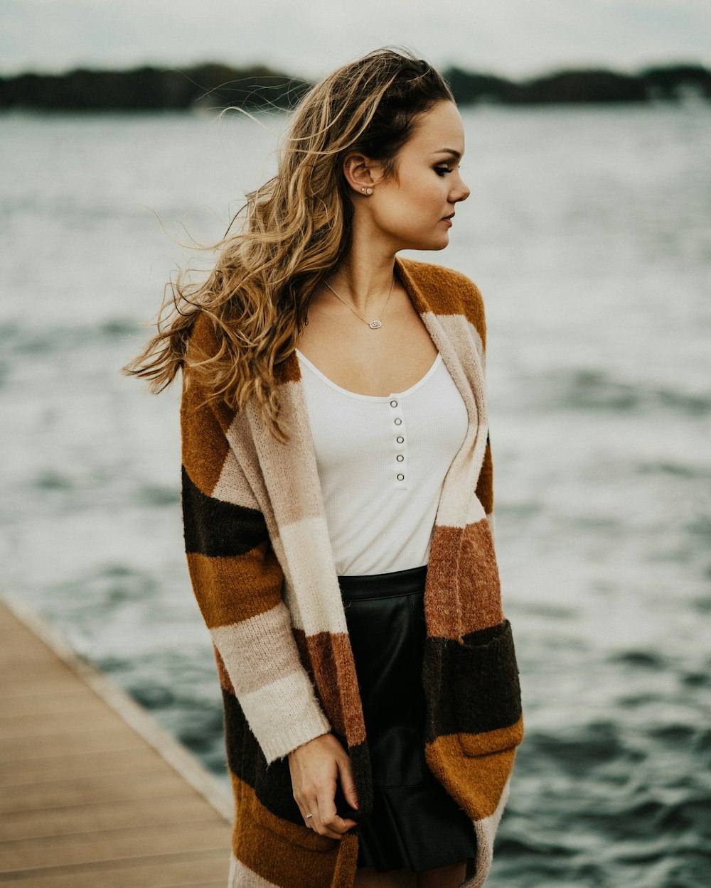 Mujer con abrigo marrón, negro y blanco en el muelle