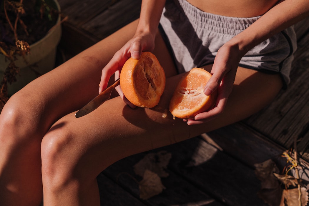 person holding sliced orange fruit on human laps