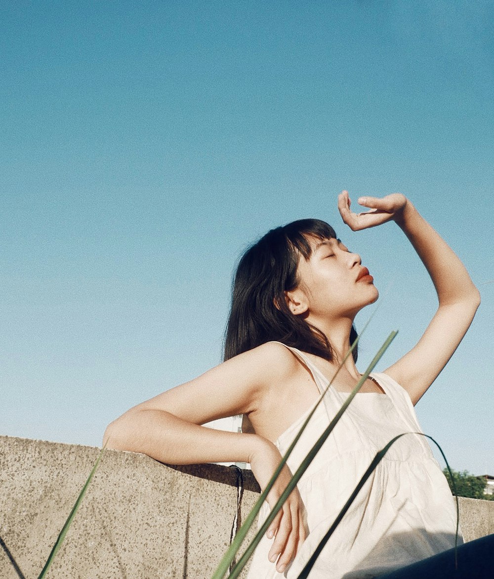 woman leaning on wall covering her face