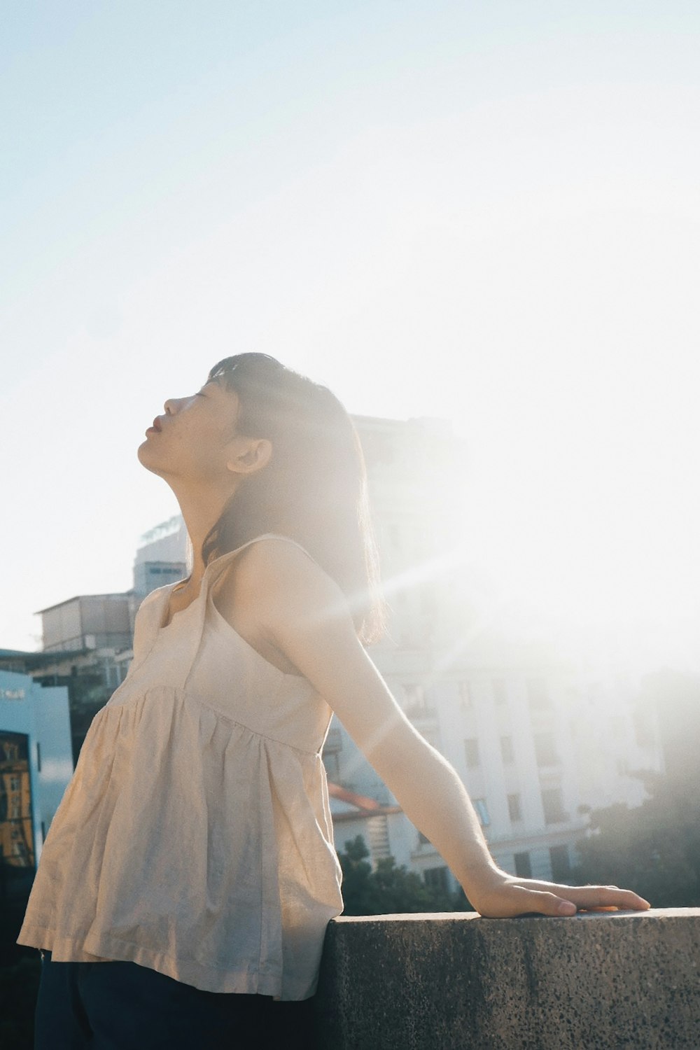 woman wearing white tank top standing in front of gray wall