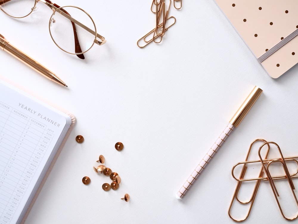 book beside thumbtacks, pens, paperclips, and eyeglasses