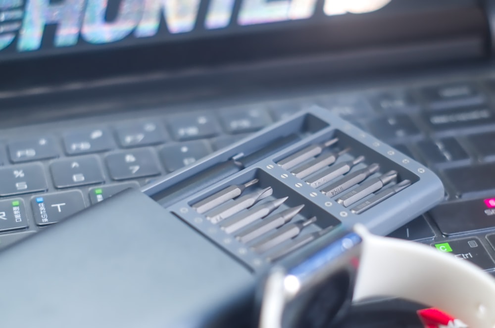 검은색 컴퓨터 키보드 위에 있는 케이스에 회색 드라이버 세트