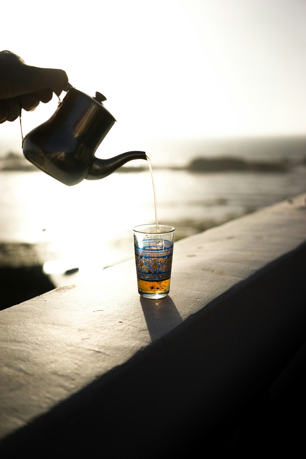 tetera gris vertiendo líquido marrón en un vaso