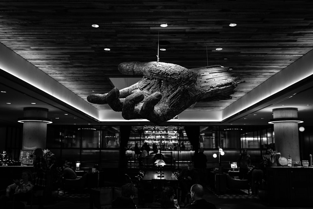grayscale photography of restaurant with 3D hand ceiling