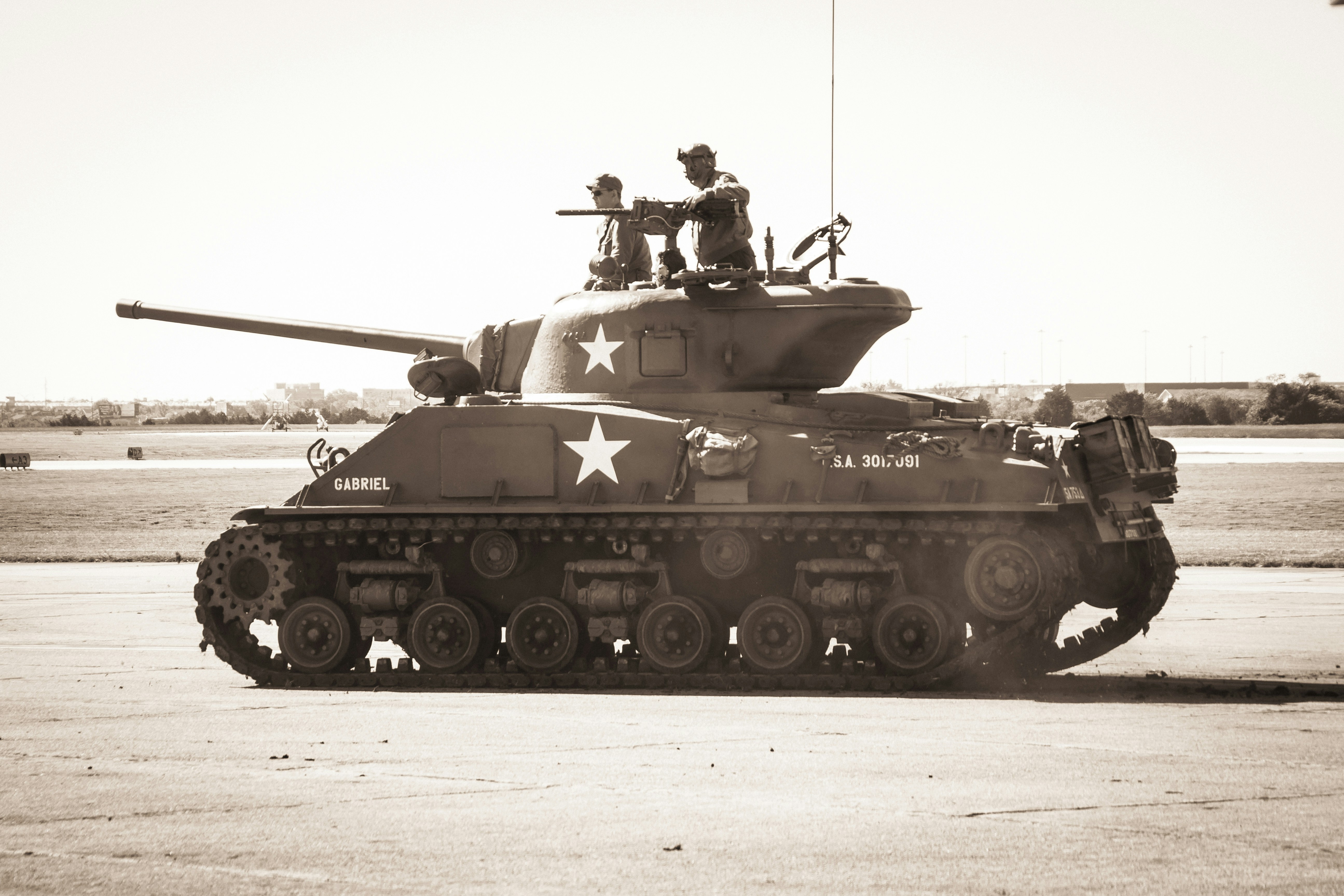 two people riding on battle tank