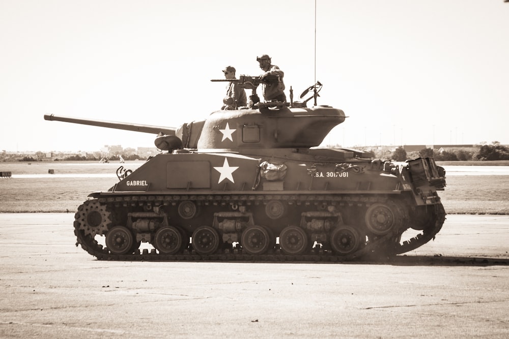 two people riding on battle tank