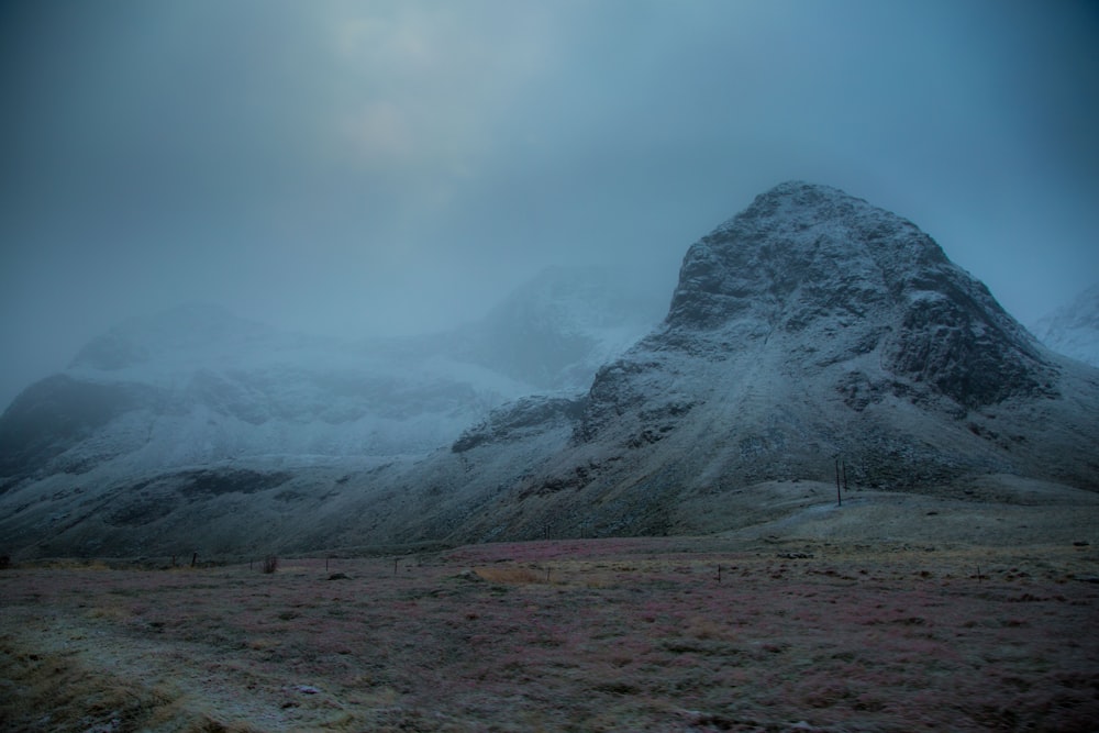 a snow covered mountain in the middle of a field