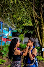 A peaceful scene showing a person receiving jagua body painting surrounded by natural elements.