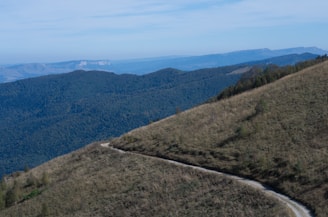 A winding pilgrimage trail leading toward distant mountains under a calm sky.